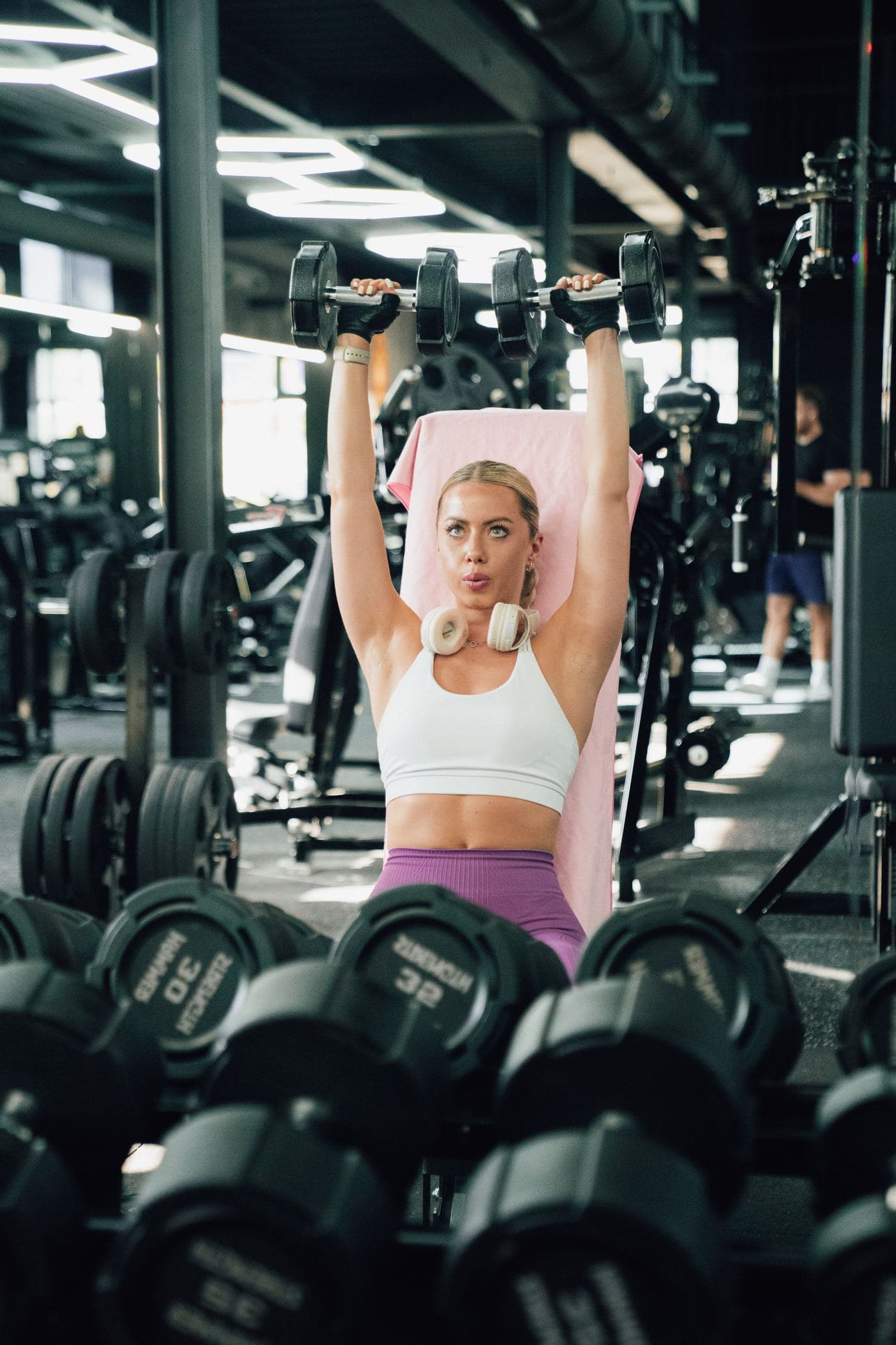 Členka Gladiator Gymu pri tlaku jednoručiek nad hlavu